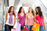 four women walking together holding shopping bags