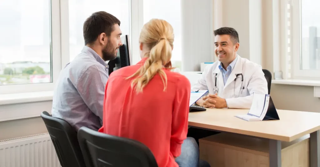 Uterine endoscopy discussion with a smiling doctor meeting a couple in a bright medical consultation room.