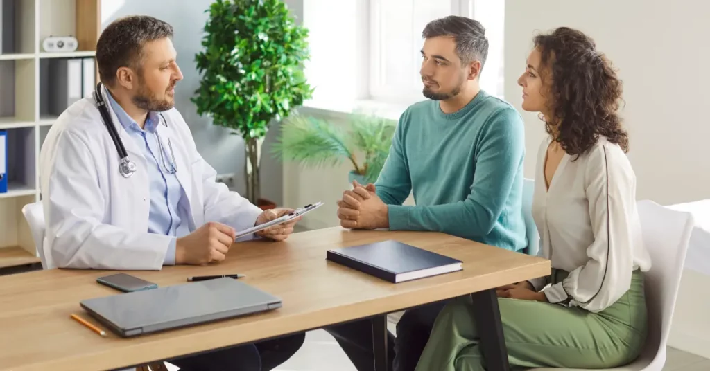 Hysteroscopy preparation discussion between a doctor and couple holding medical documents and smiling in a clinic