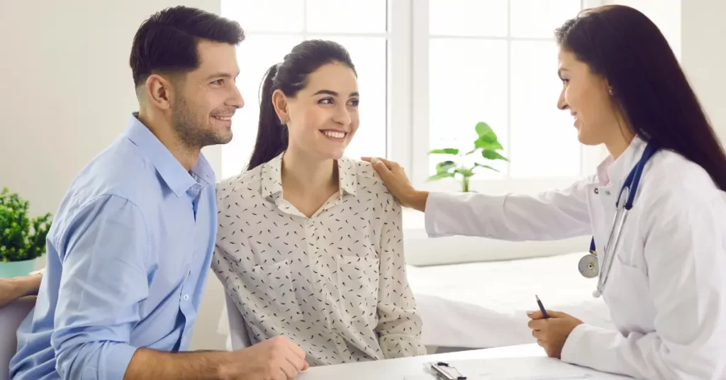 Fertility medication options discussed with a smiling couple and doctor in a bright clinical setting.