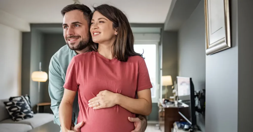 In vitro fertilization service couple smiling and embracing at home during pregnancy