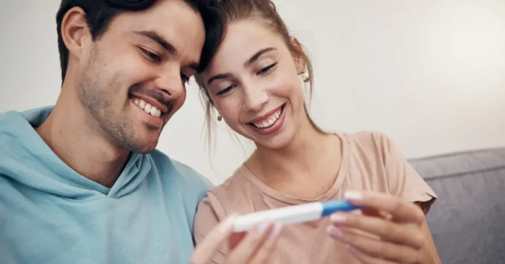 IVF treatment center couple smiling at positive pregnancy test in home environment.