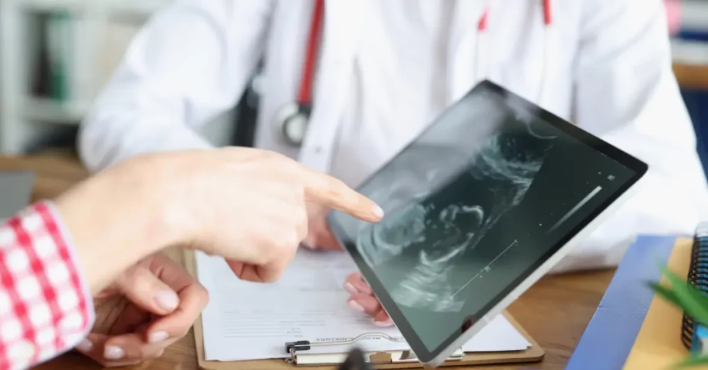Reproductive clinic doctor showing ultrasound on tablet to patient during consultation.