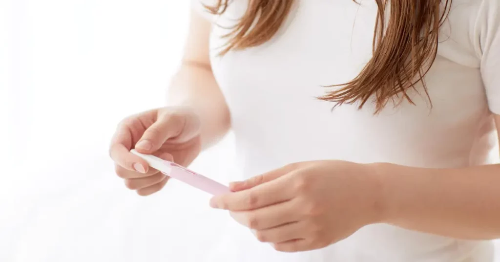 Ovarian reserve and AMH hormone concept shown by a woman holding a pink pregnancy test in bright lighting.