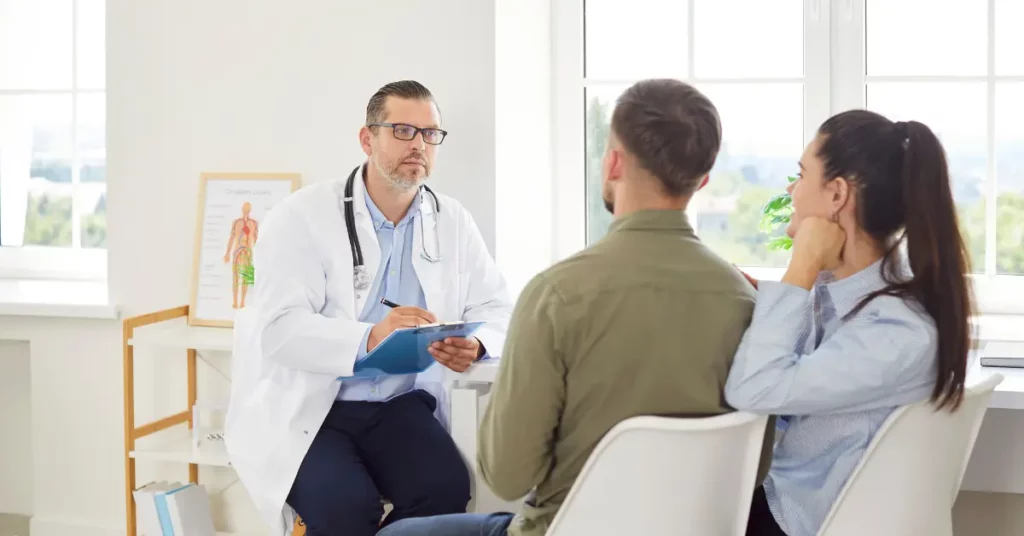 IVF clinic consultation with a doctor speaking to a couple during a fertility evaluation in a bright medical office.