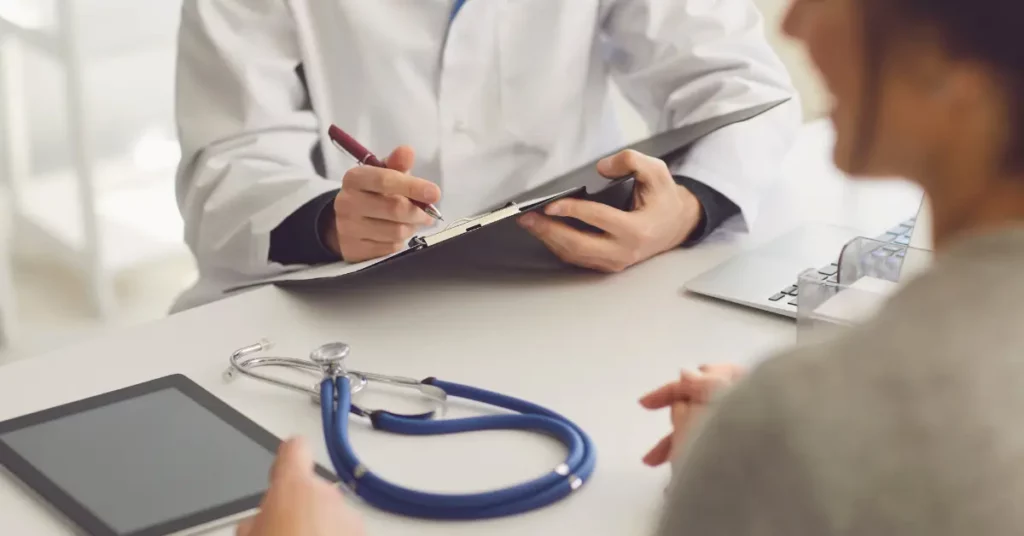 Fertility clinic services discussion between a patient and doctor at a desk with a stethoscope, tablet, and clipboard.