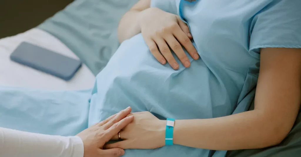 Fertility services support a pregnant woman lying in a hospital bed with hands on her belly