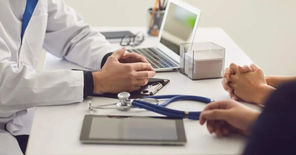 Reproductive health tests by gender discussed between a doctor and couple at a desk with medical tools and documents.