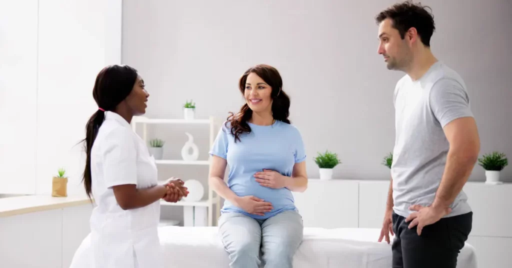 Mild IVF treatment consultation with a pregnant woman and her partner talking to a female healthcare provider.