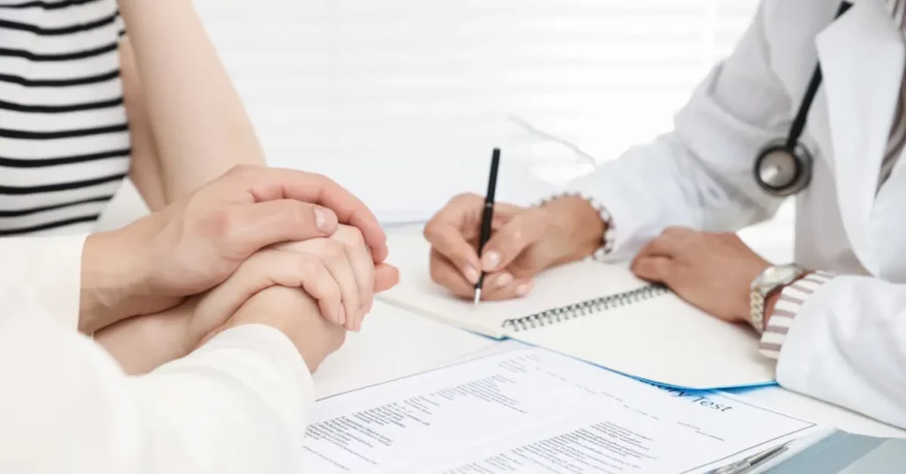 ICSI full procedure discussed by a couple holding hands during a medical consultation with a doctor writing notes.