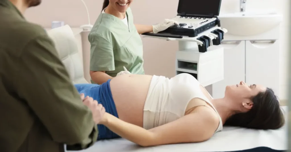 Fertility consultation appointment with a pregnant woman receiving an ultrasound scan while holding her partner's hand.