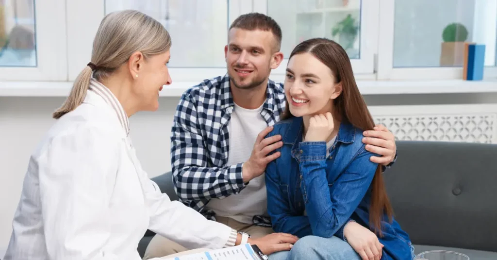 Male fertility testing consultation with a smiling couple meeting a fertility specialist in a bright clinic.