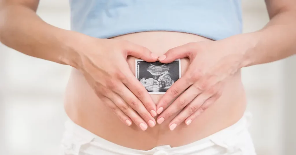 Assisted conception services represented by a pregnant woman holding an ultrasound image over her belly.