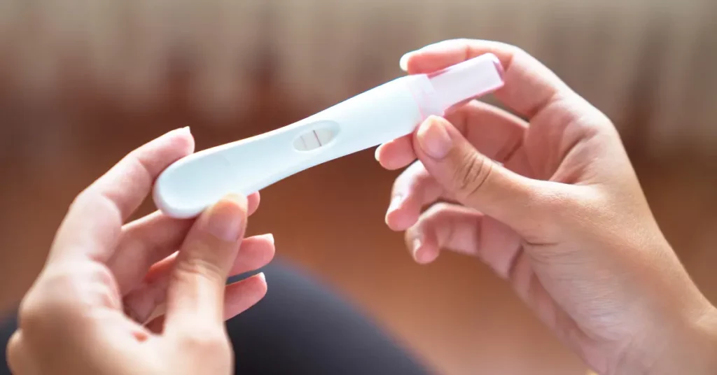 Nutrients for ovulation highlighted by a positive pregnancy test held by a woman’s hands.